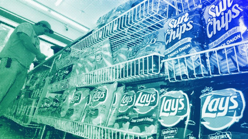 A convenience store customer make a purchase next to a shelf of snacks, in Boston, July 2005