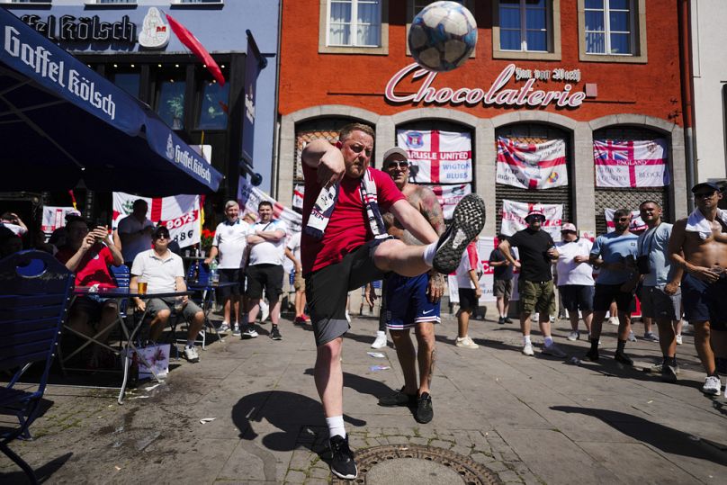 Un fan anglais frappe un ballon alors qu'il se rassemble avec d'autres supporters avant un match du groupe C entre l'Angleterre et la Slovénie lors du tournoi de football Euro 2024 dans le centre-ville de Cologne.