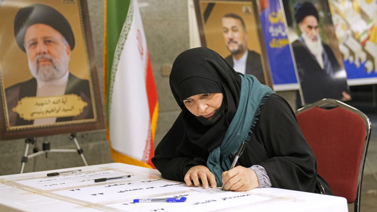 A woman casts her vote during the presidential election at a polling station inside the Iranian embassy in Baghdad, Iraq, Friday, June 28, 2024.