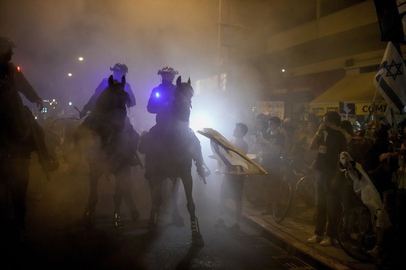 Des policiers à cheval israéliens dispersent des manifestants bloquant une route lors d'une manifestation contre le gouvernement du Premier ministre israélien Benjamin Netanyahu, juin 2024.