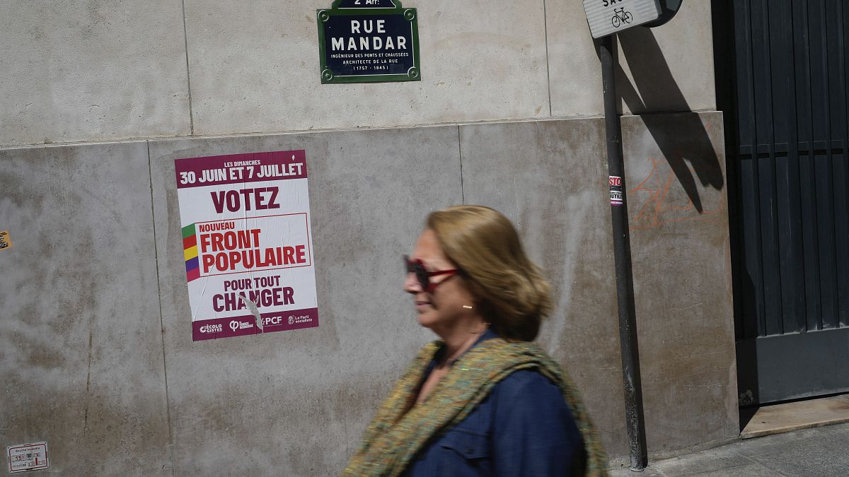 A woman walks past a poster reading