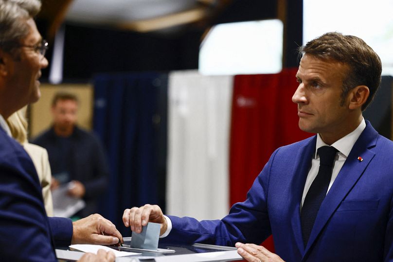 Le président français Emmanuel Macron, à droite, dépose son bulletin de vote pour le premier tour des élections législatives anticipées françaises, au Touquet-Paris-Plage, dans le nord de la France.