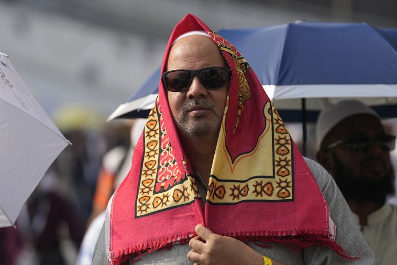 Un pèlerin se couvre la tête d'un tapis de prière pour se protéger du soleil lorsqu'il part après avoir prié à l'extérieur de la Grande Mosquée lors du pèlerinage annuel du Hajj.