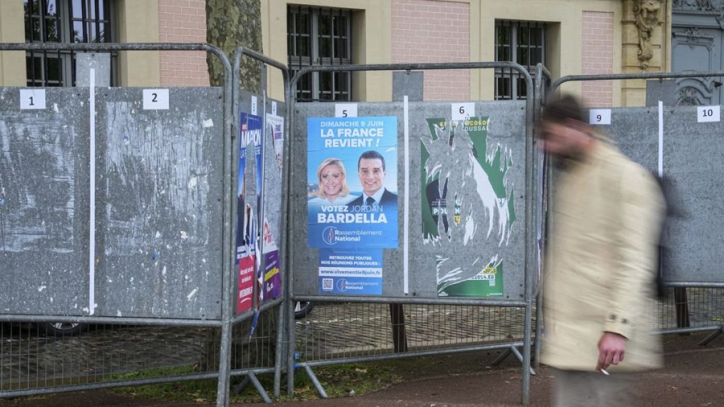 A man walks past a row of campaign boards for the upcoming European election in Versailles west of Paris, Friday, May 31, 2024.