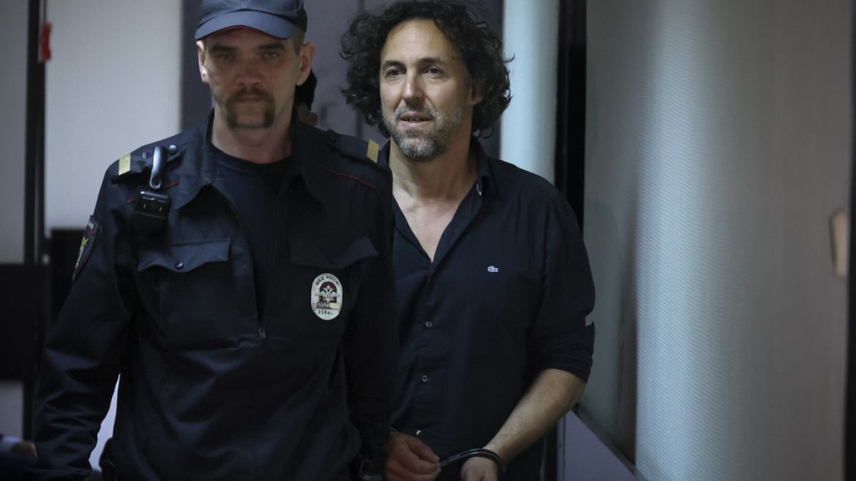 French citizen Laurent Vinatier, right, is escorted into a cage in a courtroom in the Zamoskvoretsky District Court in Moscow, Russia on Friday, June 7, 2024