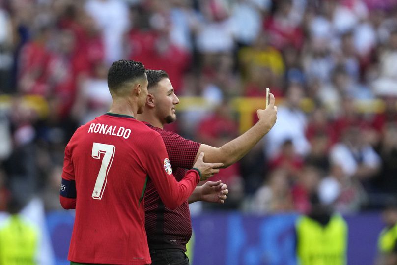 Un envahisseur de terrain prend un selfie avec le Portugais Cristiano Ronaldo lors d'un match du groupe F entre la Turquie et le Portugal lors du tournoi de football Euro 2024 à Dortmund, en Allemagne.