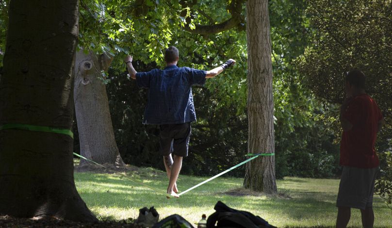 Un garçon s'exerce à son équilibre sur une sangle placée entre deux arbres dans un parc de Gand, juin 2020