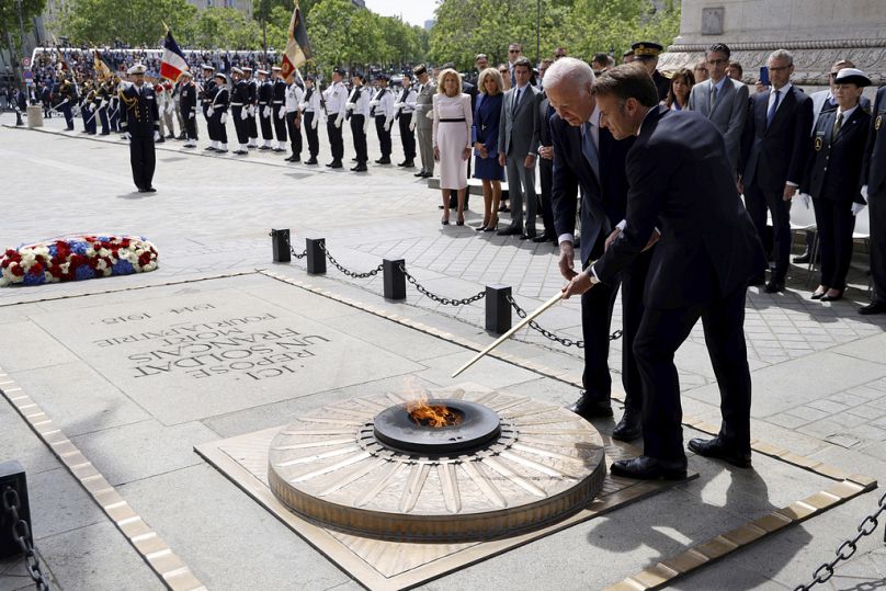 Le président français Emmanuel Macron, à droite, et le président américain Joe Biden ravivent la flamme de la Tombe du Soldat inconnu lors d'une cérémonie à l'Arc de Triomphe, samedi juillet