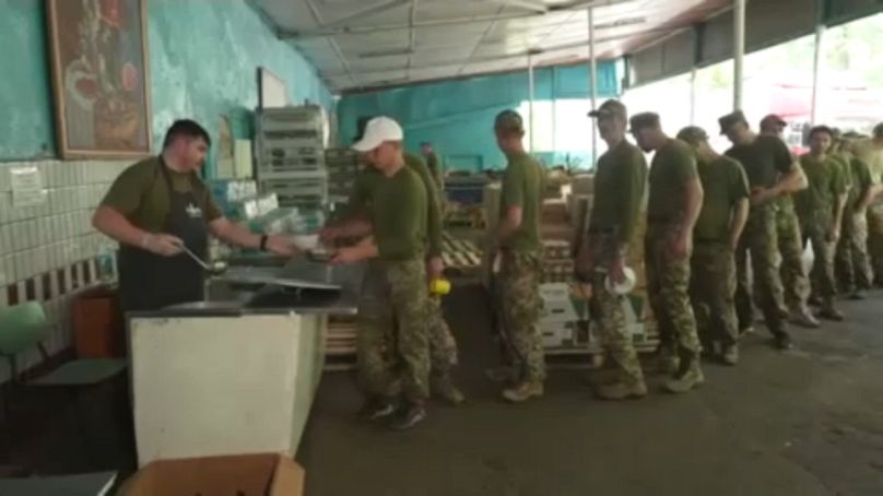 D'anciens détenus font la queue pour obtenir de la nourriture au camp d'entraînement militaire.