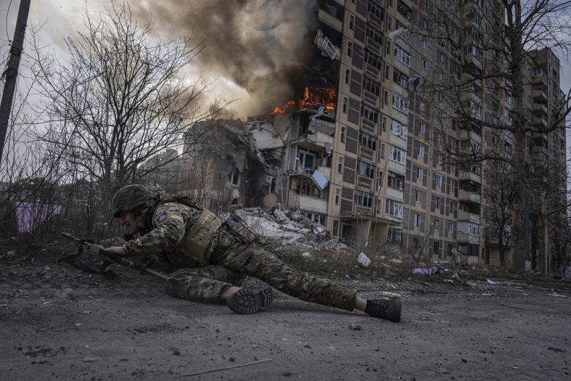   Un policier ukrainien se met à couvert devant un bâtiment en feu qui a été touché lors d'une frappe aérienne russe à Avdiivka, en Ukraine, le vendredi 17 mars 2023.
