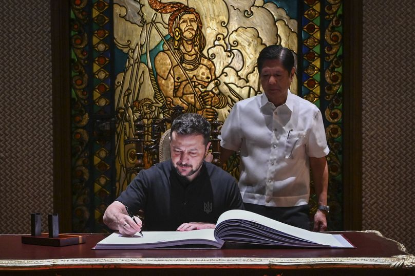 Le président ukrainien Volodymyr Zelenskyy, à gauche, signe le livre d'or aux côtés du président philippin Ferdinand Marcos Jr. au palais présidentiel de Malacanang à Manille, 2024.