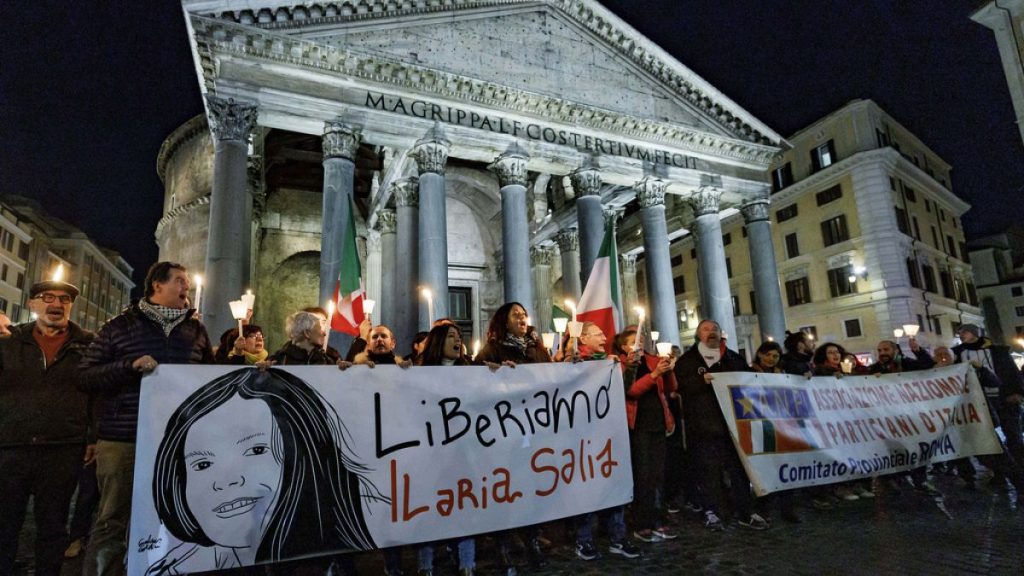 Demonstrators hold up a banner at left with writing reading in Italian