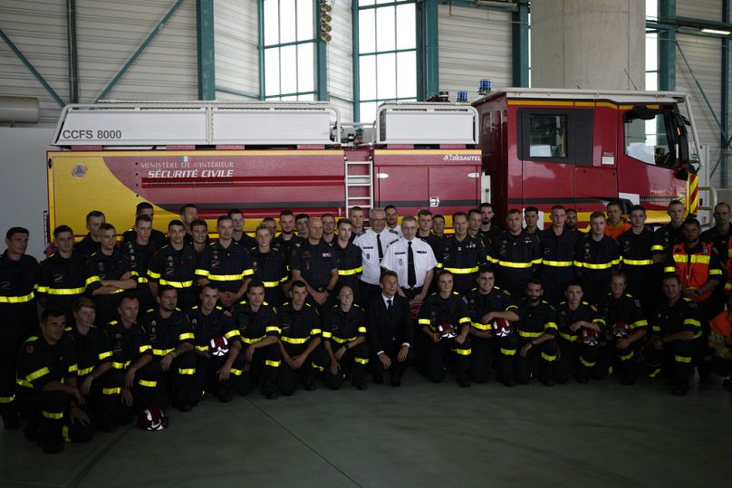Le président français Emmanuel Macron (au centre) pose avec des secouristes et des pompiers à la base aérienne des pompiers de Nîmes-Garons en 2023