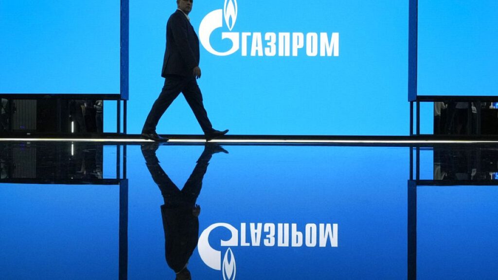 A man walks at an exhibition at the St. Petersburg International Gas Forum in St. Petersburg, Russia, Wednesday, Sept. 14, 2022, with a logo of Russian gas monopoly Gazprom in