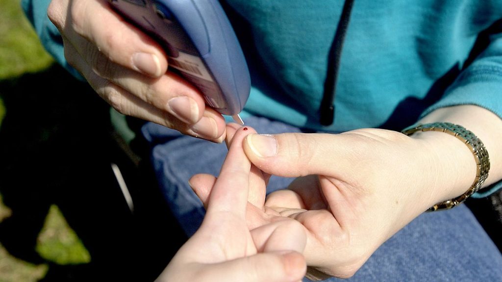 A young person has her blood sugar tested.