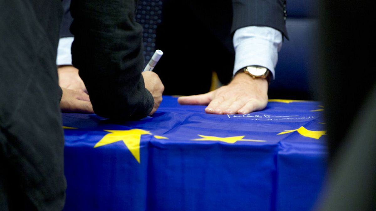 Eurogroup finance ministers sign an EU flag during a round table meeting of eurogroup finance ministers in Luxembourg, Monday, Oct. 9, 2017.