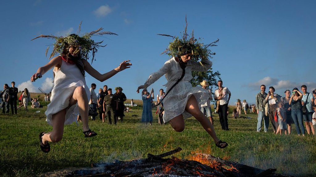 Ukrainian women jump over the fire at a traditional Midsummer Night celebration near capital Kyiv, Ukraine, Sunday, June 23, 2024.