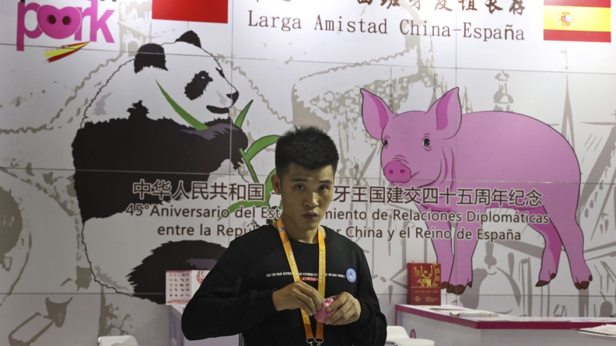 A promoter at a booth for imported Spanish pork prepares for another day at the China International Import Expo in Shanghai, on Nov. 6, 2018