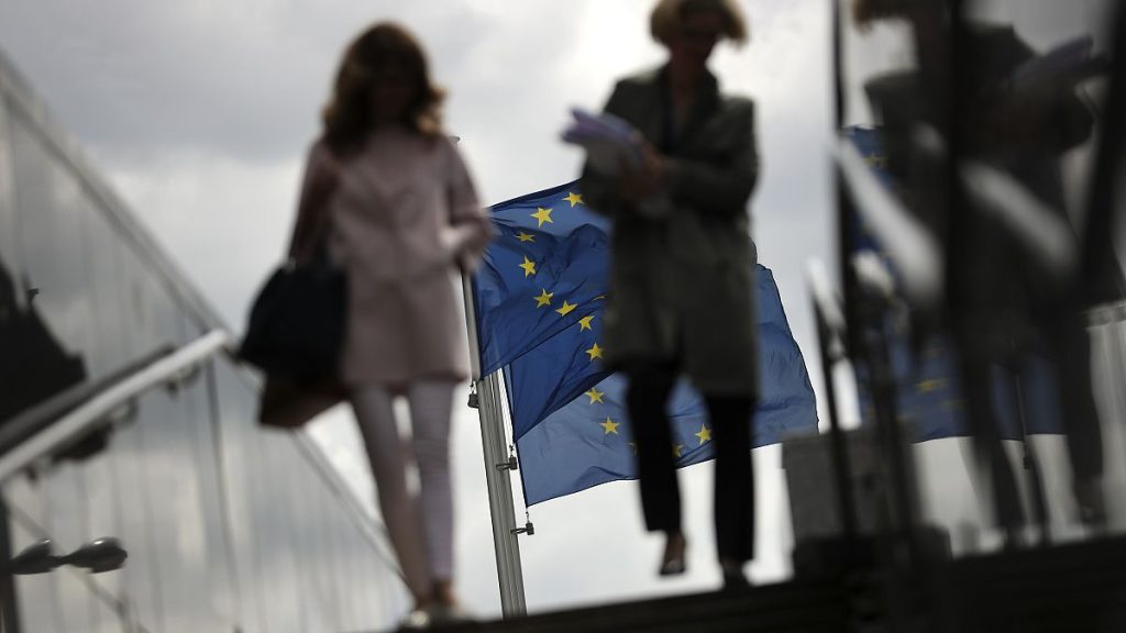 FILE - Two women walk near EU flags outside the European Commission headquarters in Brussels, Monday, May 27, 2019.