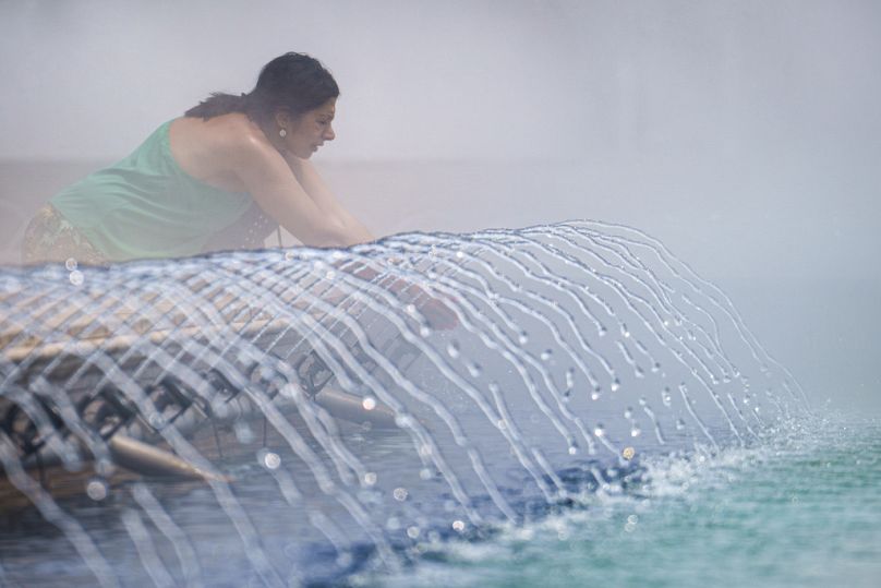 Une femme se rafraîchit près d’une fontaine publique à Bucarest, en Roumanie, le mercredi 19 juin 2024.