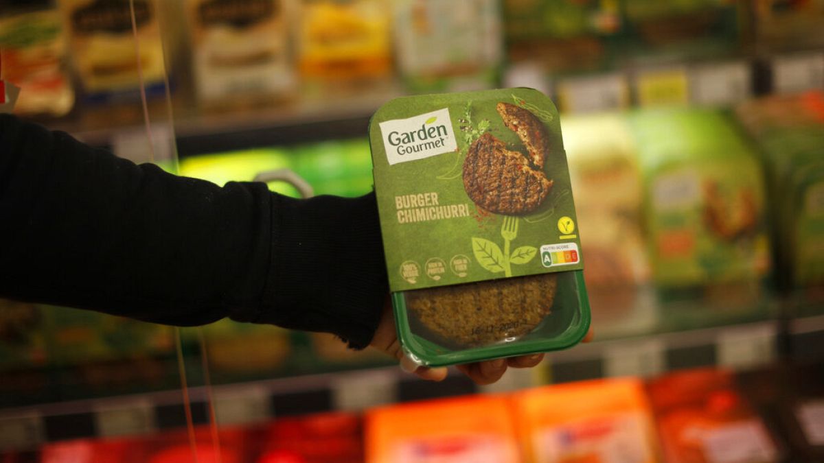 A store clerk shows a plant based burger at a supermarket chain in Brussels, Friday, Oct. 23, 2020.