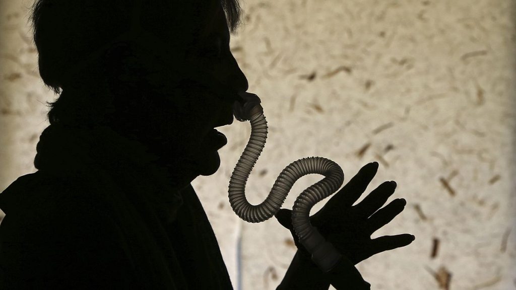 A woman demonstrates how she puts on her sleep apnea breathing device at her home in Los Angeles.