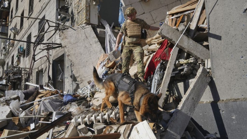 A rescue worker with a dog search for victims in a damaged apartment building after it was hit by Russian air bomb in Kharkiv, Ukraine, Saturday, June 22, 2024.