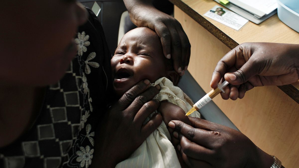 A mother holds her baby receiving a new malaria vaccine as part of a trial in Kenya.