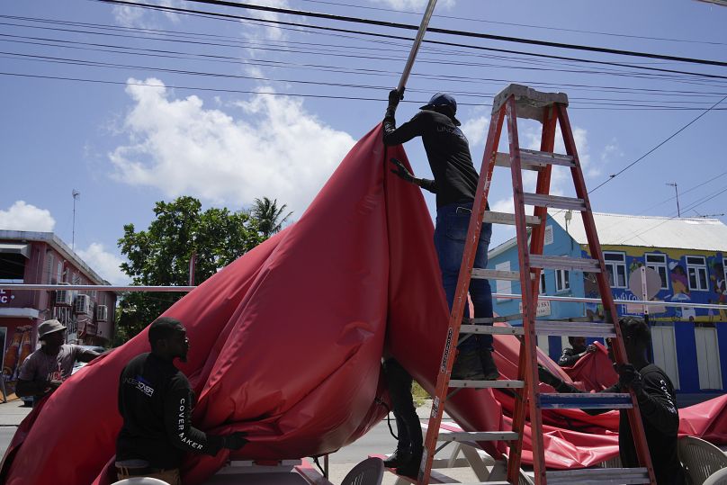 Des gens démontent l'auvent d'un bar de plage en prévision de l'ouragan Beryl, à Bridgetown, à la Barbade.