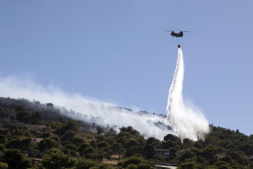 Un hélicoptère de lutte contre les incendies jette de l'eau sur un incendie de forêt dans la région de Keratea, au sud-est d'Athènes, en Grèce.