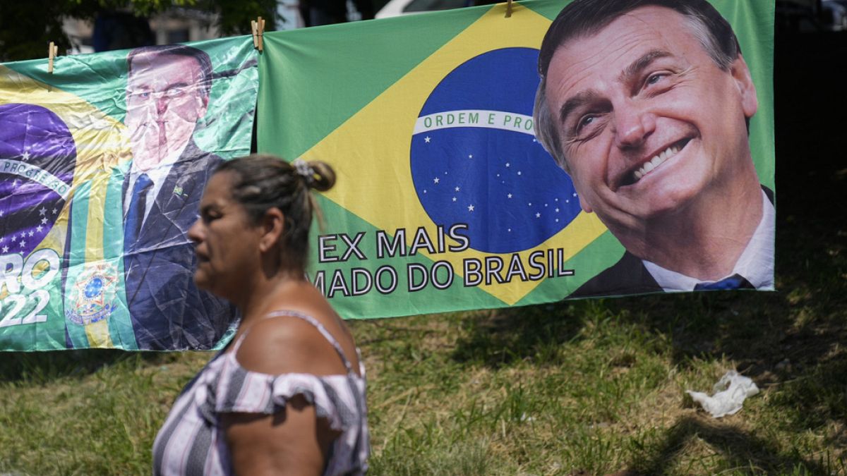 A woman walks past a banner featuring the Brazilian national flag and an image of former President Jair Bolsonaro.