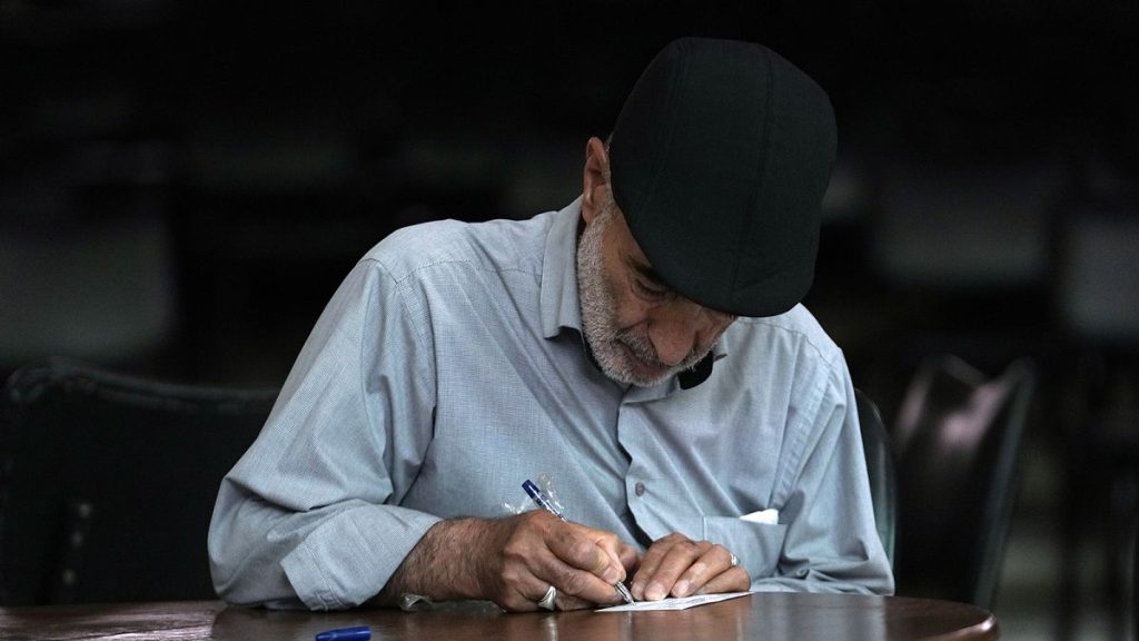 An Iranian man fills out his ballot for the presidential runoff election at a polling station in Tehran, 5 July 2024