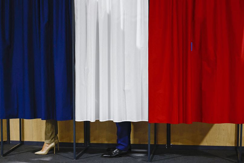 Le président français Emmanuel Macron et son épouse Brigitte Macron se tiennent dans l'isoloir avant de voter au Touquet-Paris-Plage, le 30 juin 2024