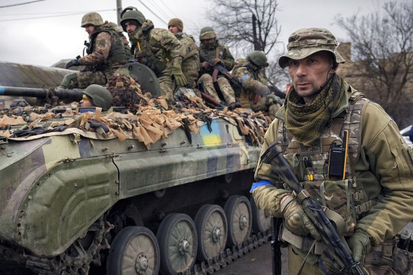 Un militaire ukrainien marche à côté d'un véhicule de combat, à l'extérieur de Kiev, le 2 avril 2022