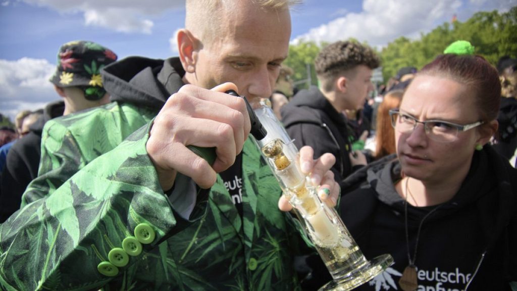 A man smokes as people celebrate at the Brandenburg Gate during a rally and festival to legalise cannabis, in Berlin in April