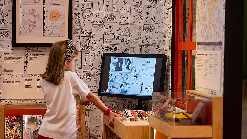 Une jeune fille regarde une exposition interactive, du Japon : des mythes au manga au Young V&A. 