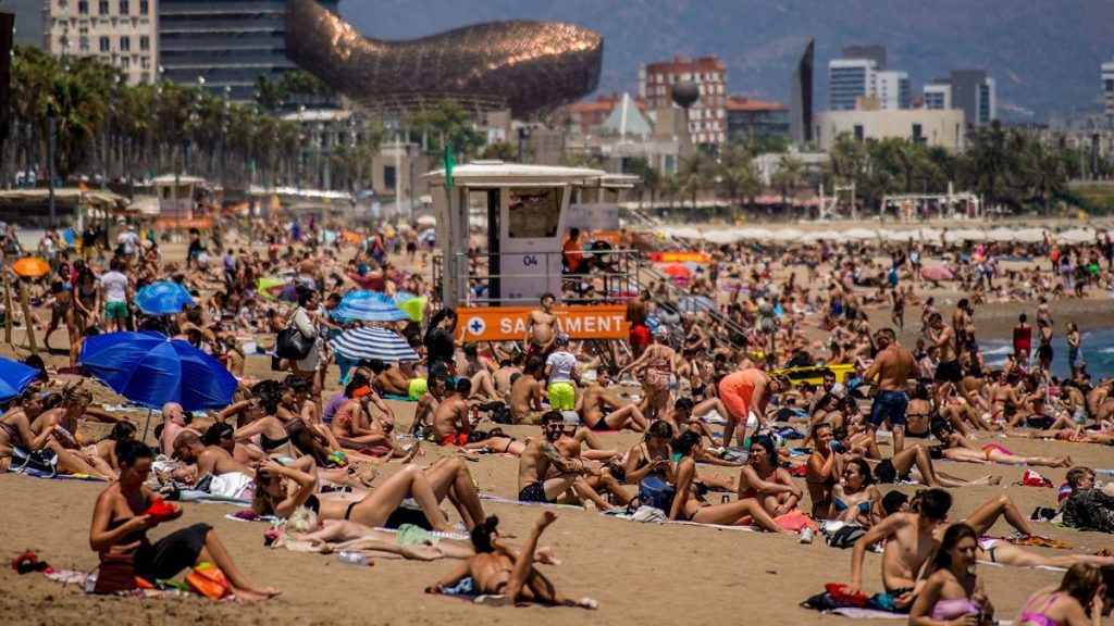 People sunbathe on the beach in Barcelona, Spain, 9 July 2021.