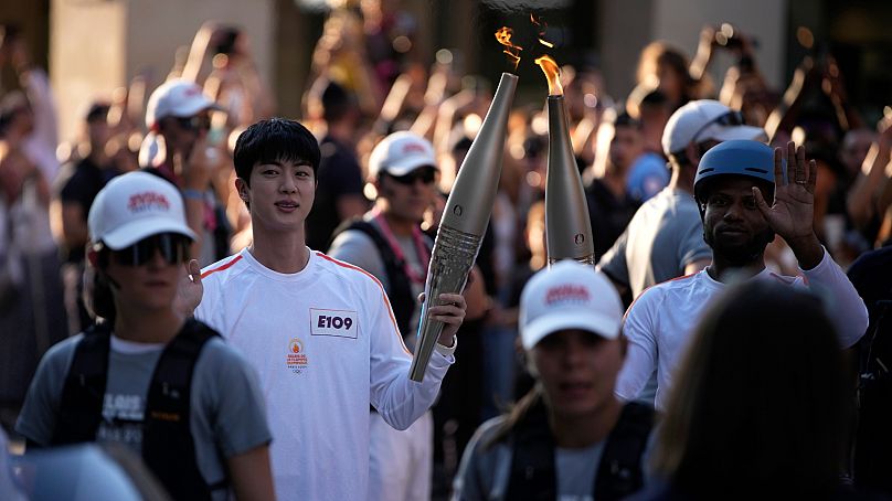 Jin, à gauche, le membre le plus âgé du supergroupe de K-pop BTS, prend la torche olympique, dimanche 14 juillet 2024