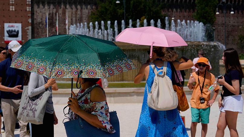 Les touristes s'abritent du soleil devant le château Sforzesco à Milan, en Italie, le 16 juillet 2024.