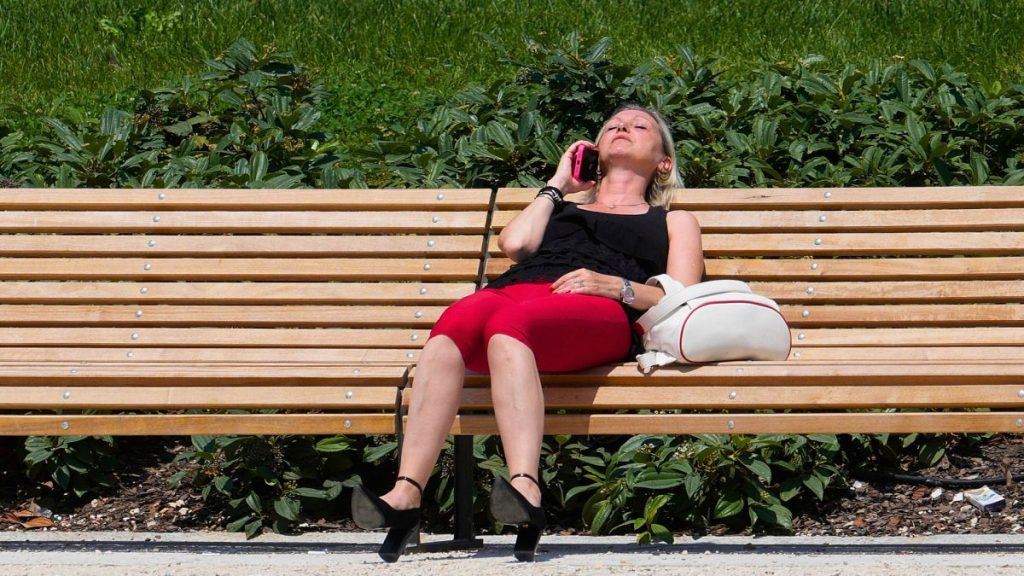 A woman sits in a park in Milan, Italy, Tuesday, 16 July 2024.