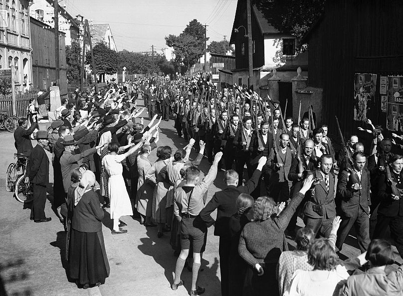 Des Allemands des Sudètes du Corps franc reçoivent le salut nazi alors qu'ils traversent Haslow alors qu'ils retournent en Tchécoslovaquie le 22 septembre 1938. 