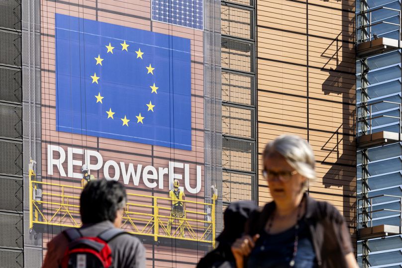   Des piétons marchent devant une banderole devant le siège de l'UE avant un sommet européen à Bruxelles, en juin 2024