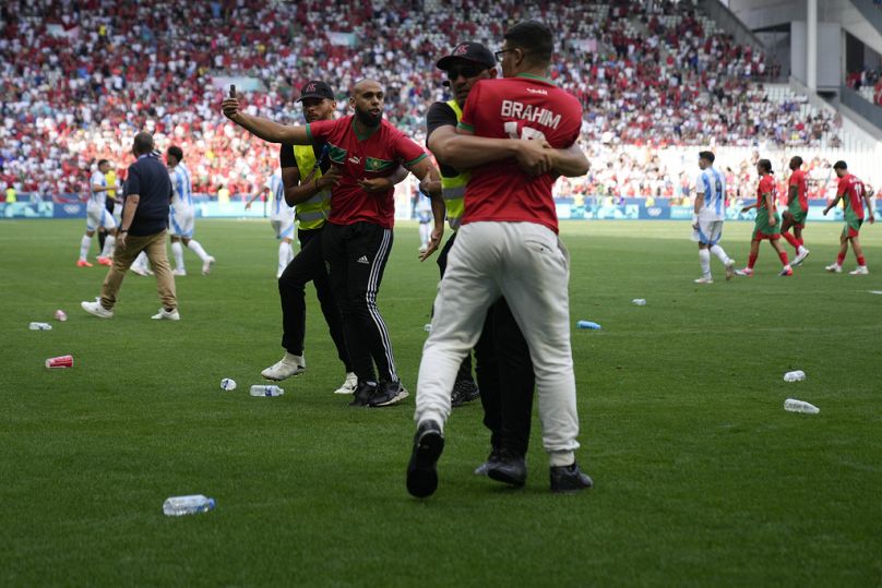 Les stewards interceptent des envahisseurs de terrain lors du match du groupe B masculin entre l'Argentine et le Maroc au stade Geoffroy-Guichard de Saint-Étienne