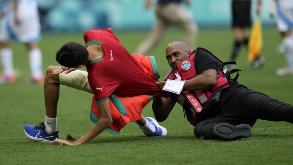 A steward catches a pitch invader during the men