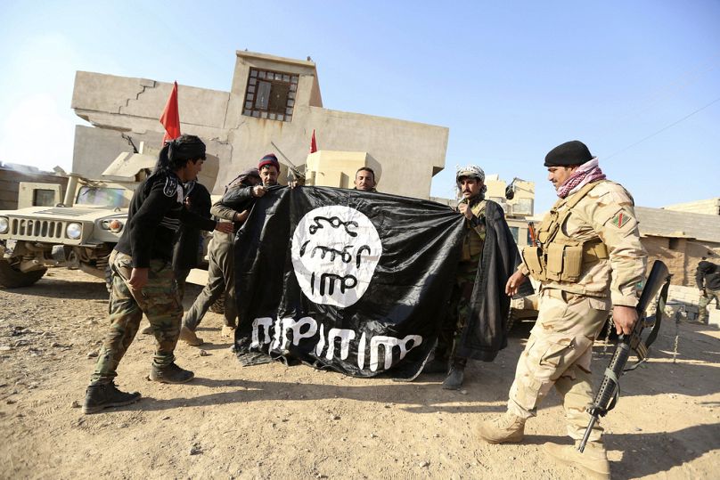 Des soldats de l'armée irakienne célèbrent en tenant un drapeau du groupe État islamique qu'ils ont capturé lors d'une opération militaire pour reprendre le contrôle d'un village à l'extérieur de Mossoul, en Irak.