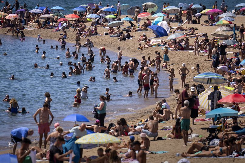 Les baigneurs se rafraîchissent dans l'eau tandis que d'autres prennent le soleil sur une plage de Barcelone.