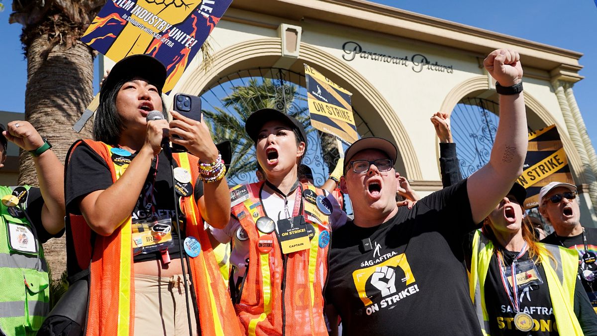 SAG-AFTRA captains Iris Liu, left, and Miki Yamashita, center, and SAG-AFTRA chief negotiator Duncan Crabtree-Ireland lead a cheer for striking actors in 2023