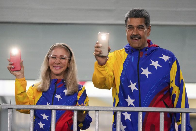 Le président Nicolas Maduro et la première dame Cilia Flores allument les lampes de poche de leurs téléphones portables après avoir voté aux élections présidentielles à Caracas, au Venezuela, dimanche.