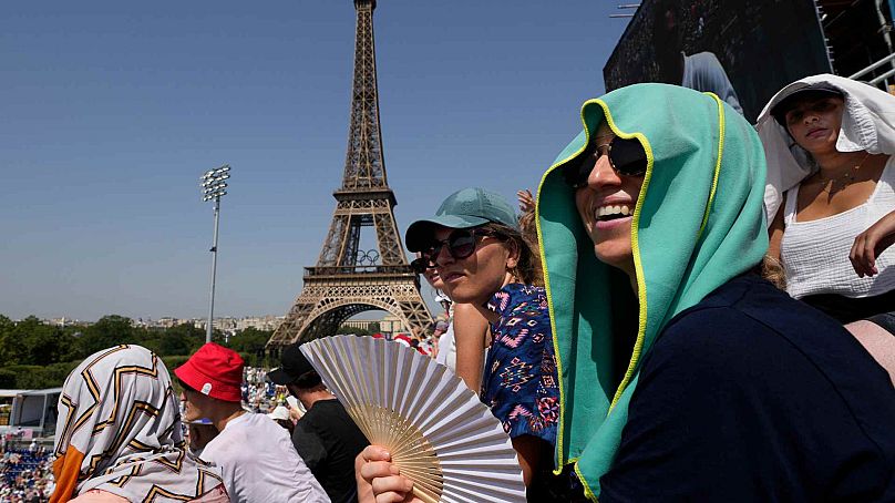 Stéphanie Touissaint, au premier plan, utilise un ventilateur pour se rafraîchir dans la chaleur étouffante du stade de la Tour Eiffel lors d'un match de beach-volley aux Jeux olympiques d'été de 2024