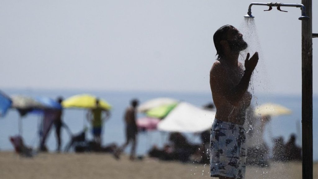 A man takes a shower on a beach on a hot day in Ostia, near Rome, Aug. 23, 2023.